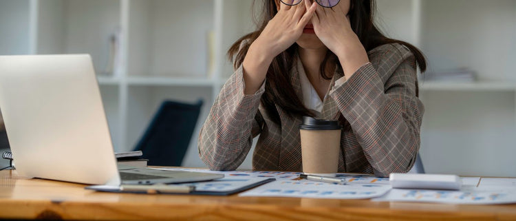 Blog of Caffeine Crash: What It is, How to Recover, & Prevention Tips which have image woman holding head in her hands at work desk