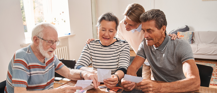 Blog of 5 Natural Ways to Improve Memory & Focus in Seniors which have image Elderly group reminiscing over photos with a younger woman.