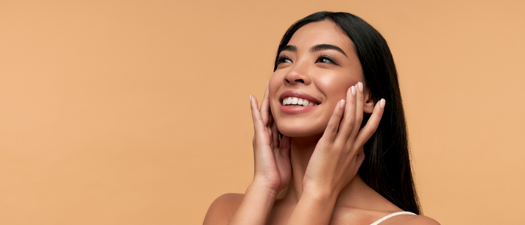 Blog of Do Zinc Supplements Really Help Acne? The Science Behind Clear Skin which have image A young woman with radiant, clear skin smiles while touching her face, set against a warm beige background.