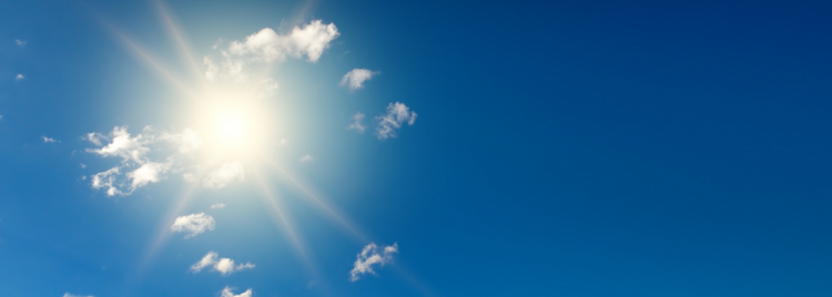 A clear blue sky with the sun shining brightly, casting radiant beams of light. 