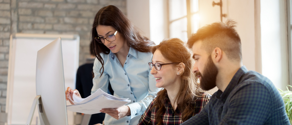 Three young professionals collaborate in a modern office setting. 