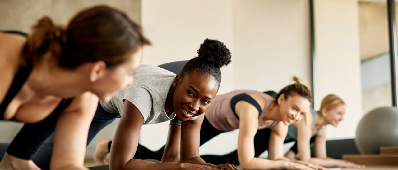 A diverse group of women in an exercise class, smiling and engaging in a fun and energetic workout session, promoting fitness, teamwork, and positivity.